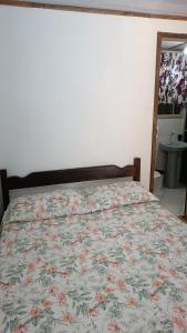 a bed with a floral comforter in a bedroom at Pousada Sobre as Ondas - ILHA DO MEL - PR in Ilha do Mel