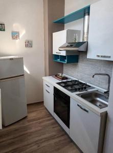 uma cozinha com um fogão branco e um lavatório em Casa 100m dal mare caraibico em Lido Marini