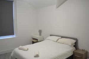 sypialnia z łóżkiem z białą pościelą i oknem w obiekcie Ashbrooke Homestay w mieście Sunderland