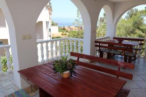 a porch with benches and tables on a balcony at Apartment Ruzmarin in Šilo