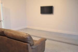 a living room with a couch and a television on a wall at Ashbrooke Homestay in Sunderland