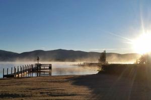 a dock with the sun rising over a body of water at Waters Edge Lodge in Lake George