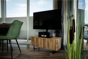 a living room with a flat screen tv on a wooden stand at Hausboot Albatros - LP4 in Laasow