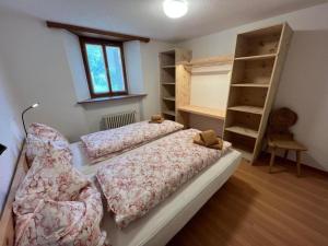 1 dormitorio con 2 camas y estanterías en Chesa Fischer Wohnung Palü ÖV-Inklusive, en Samedan