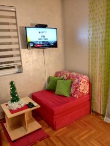ein Wohnzimmer mit einem roten Sofa und einem TV in der Unterkunft Apartman Radmanovac 2 in Vrnjačka Banja