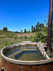 uma banheira de madeira cheia de água num campo em Cabaña Puerto Octay em Puerto Octay