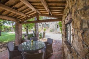 eine Terrasse mit einem Tisch, Stühlen und einer Steinmauer in der Unterkunft Antica Corte in Soave