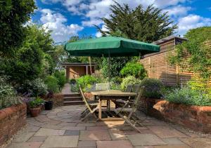 uma mesa com um guarda-chuva verde num pátio em Fern Cottage em Walberswick