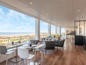 um restaurante com mesas e cadeiras e vista para o oceano em Mercure Dieppe La Présidence em Dieppe