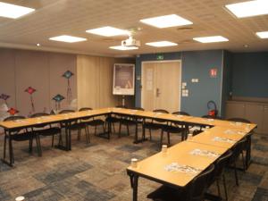 une salle de conférence avec des tables, des chaises et un écran dans l'établissement Mercure Dieppe La Présidence, à Dieppe