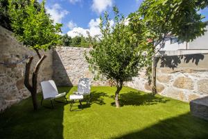 a garden with a chair and two trees in it at Guest H4U - Heroismo in Porto