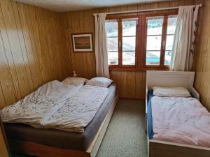 2 camas individuales en una habitación con ventana en Chalet Hasliblick Brienzwiler en Brienzwiler