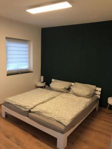 um quarto com uma cama com uma parede verde em Schöfferles Ferienwohnung em Keidelheim