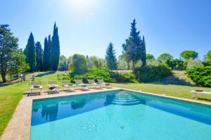 a swimming pool with lounge chairs next to a yard at Villa Piandisette in Cetona