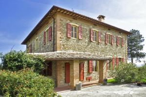 an old stone house with red shuttered windows at Villa Piandisette in Cetona