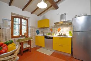cocina con armarios amarillos y nevera de acero inoxidable en Villa Piandisette, en Cetona