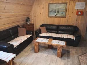 a living room with leather couches and a coffee table at Chata Zuzka pod Babou horou in Oravská Polhora