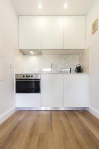 a kitchen with white cabinets and a sink at Guest H4U - Heroismo in Porto