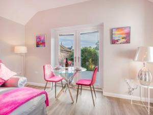 um quarto com uma mesa de vidro e cadeiras cor-de-rosa em 1 Bed in Edenhall SZ604 em Edenhall