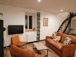a living room with two couches and a flat screen tv at Gîte du noisetier aux Granges du Vilaret in Clairvaux-les-Lacs