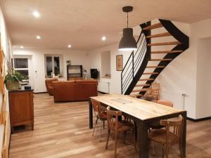 a living room with a dining room table and a staircase at Gîte du noisetier aux Granges du Vilaret in Clairvaux-les-Lacs