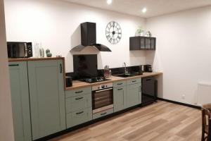 a kitchen with white cabinets and a stove top oven at Gîte du noisetier aux Granges du Vilaret in Clairvaux-les-Lacs