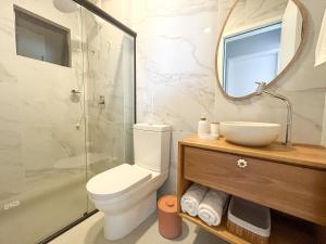 y baño con aseo, lavabo y espejo. en Bossa Mar Apartamento, en Bombinhas