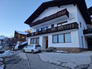 a white house with a car parked in front of it at Apartment Aghel in Ortisei