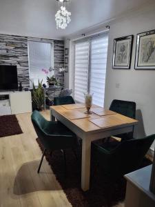 a dining room with a wooden table and green chairs at Beautiful apartment in SW London in Sutton