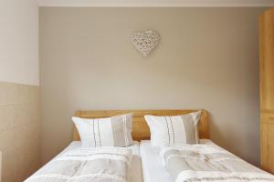 two beds with white sheets and a heart on the wall at Kiefernglück App 7 in Norderney