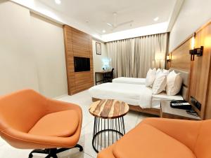 ein Hotelzimmer mit einem Bett und zwei Stühlen in der Unterkunft The Sky Imperial Hotel Kailash in Jamnagar