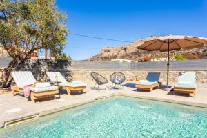 een zwembad met stoelen en een parasol naast een zwembad bij La Casa Di Pietre 1 in Kiotari