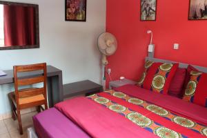 Dormitorio rojo con cama y escritorio en Umusambi B&B, en Kigali