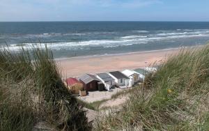 eine Reihe von Häusern an einem Strand neben dem Meer in der Unterkunft Zomerhuisje Wijk aan Zee in Wijk aan Zee