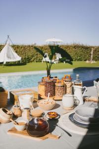 una mesa con comida y utensilios junto a una piscina en Casa L-N-Noa Boutique room whit private pool, en Lagos