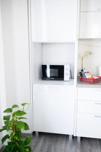 a white kitchen with a microwave in a white cabinet at Apartament Radiana in Baile Felix