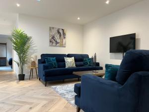 uma sala de estar com sofás azuis e uma televisão em South Street Apartments em Isleworth