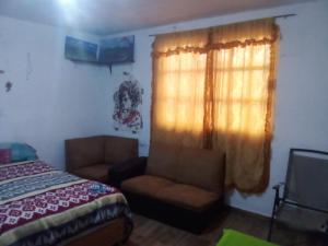 um quarto com uma cama, uma cadeira e uma janela em Tequex em Xochimancan