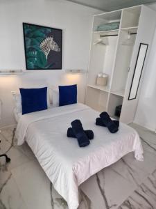 1 dormitorio blanco con 2 almohadas azules en una cama en Ático Micaela. Terraza y vistas en Santa Cruz de Tenerife