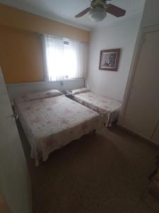 1 Schlafzimmer mit 2 Betten und einem Fenster mit einem Ventilator in der Unterkunft HOTEL MILESI NECOCHEA in Necochea