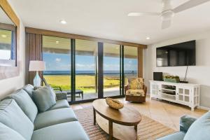 uma sala de estar com um sofá azul e uma mesa em Renovated 2br Condo with Ocean Views - Alekona Kauai em Koloa