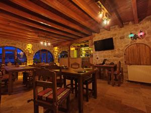 a dining room with wooden tables and chairs and a tv at Euphoria Cave House in Nar