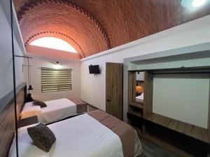 a bedroom with two beds and a large window at Hotel la Cuesta Toscana in Bernal