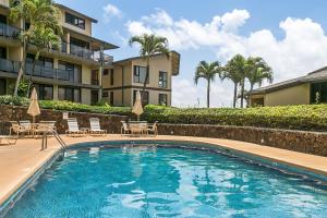 uma piscina com cadeiras e um edifício em Renovated 2br Condo with Ocean Views - Alekona Kauai em Koloa