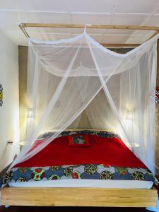 a bedroom with a bed with a red and white canopy at Isange Paradise Resort in Ruhengeri
