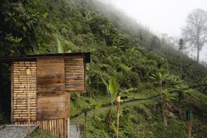 a small wooden building on a hill with a mountain at Glamping Quindio in Córdoba