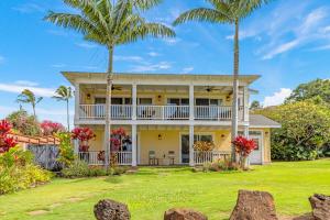 une maison avec des palmiers devant elle dans l'établissement Cute 4br home steps to the Ocean - Alekona Kauai, à Koloa