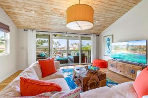 - un salon avec un canapé et une télévision dans l'établissement Cute 4br home steps to the Ocean - Alekona Kauai, à Koloa