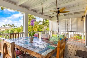 - une terrasse couverte avec une table en bois et un ventilateur de plafond dans l'établissement Cute 4br home steps to the Ocean - Alekona Kauai, à Koloa