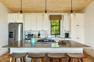a kitchen with white cabinets and a large island with bar stools at 4BR Poipu Home with Private Pool- Alekona Kauai in Koloa